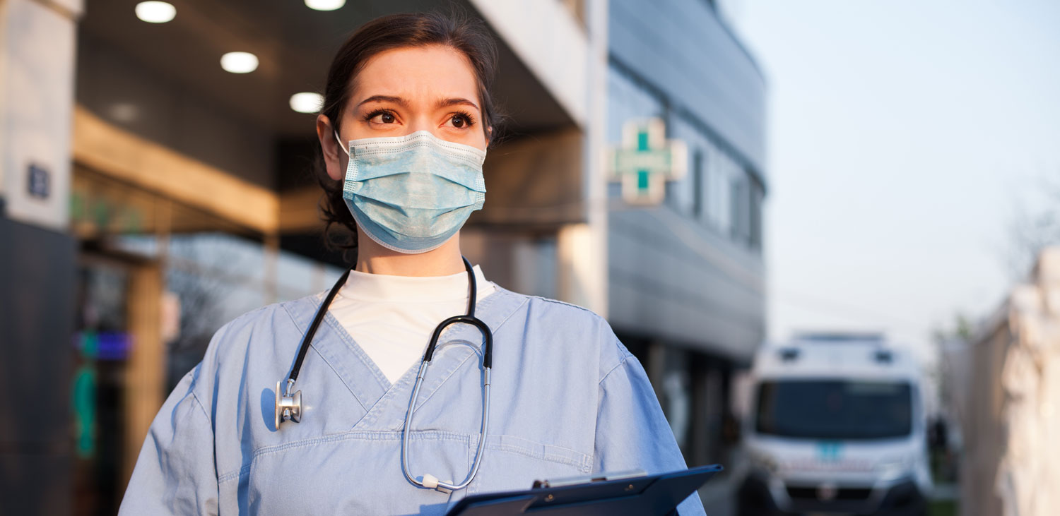 Nurse stood outside a hospital and wearing a face mask