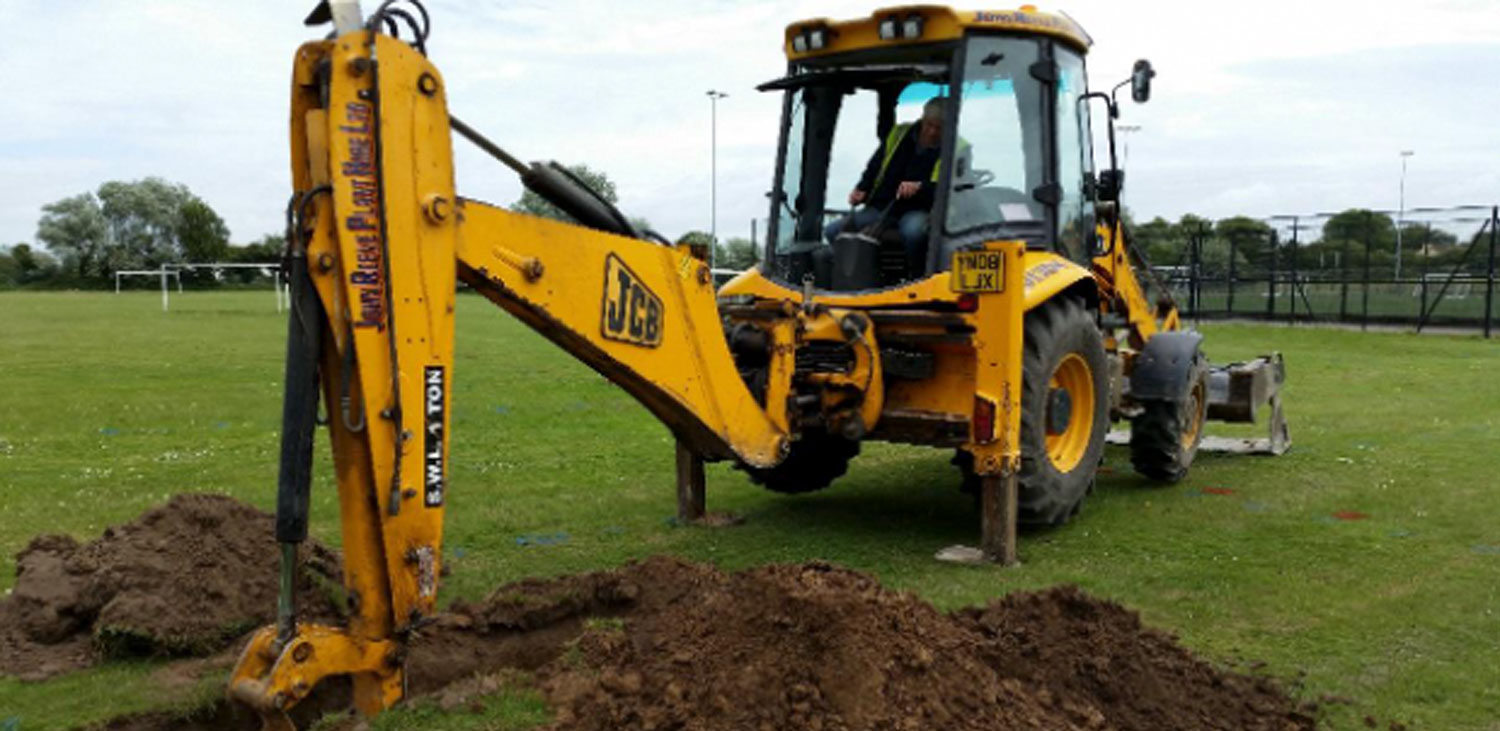 Yellow digger creating a hole in a field